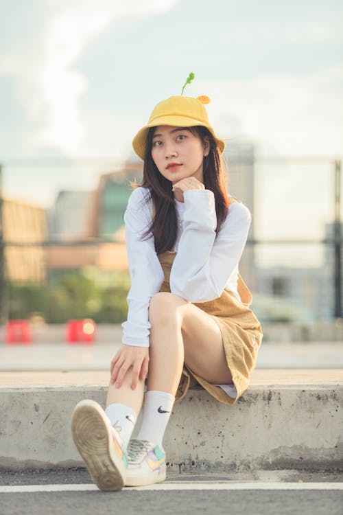 A Woman on White Long Sleeves Sitting on the Street and Posing