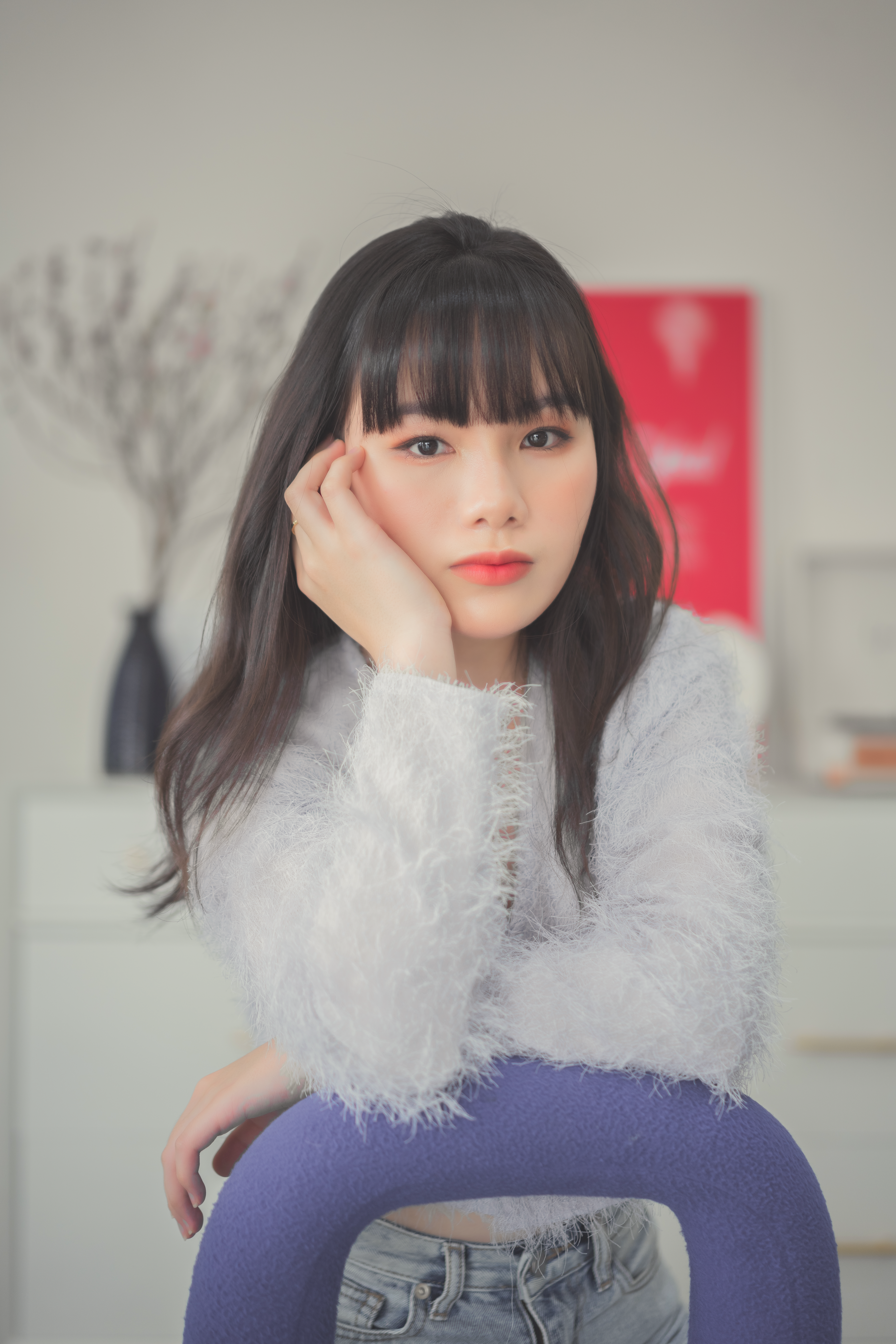 Close-up of a young woman in a fur sweater posing indoors, projecting elegance and warmth.