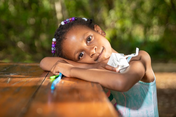 A Girl Lying On Brown Wooden Table