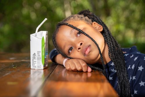 Free An African American girl resting on a wooden table with a juice box beside her. Stock Photo