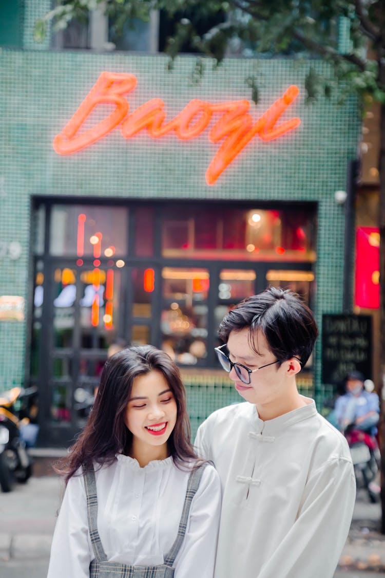 Young Couple Standing On A Street And Restaurant In Background