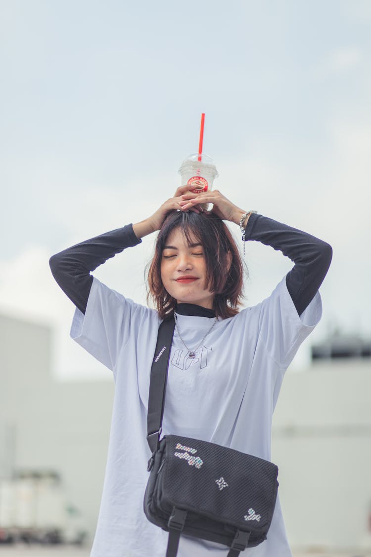 Woman Holding A Plastic Cup On Her Head 