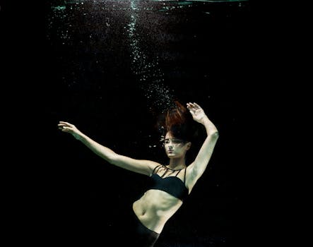 这幅迷人的水下肖像描绘了一位身着黑色比基尼的年轻女子，周围环绕着气泡