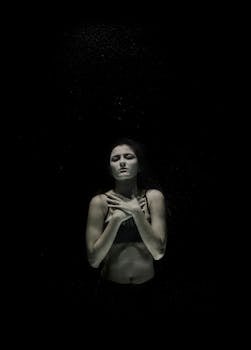 这幅水下肖像宁静而感人，捕捉了一位身穿黑衣的年轻女子，她散发着优雅而神秘的气息