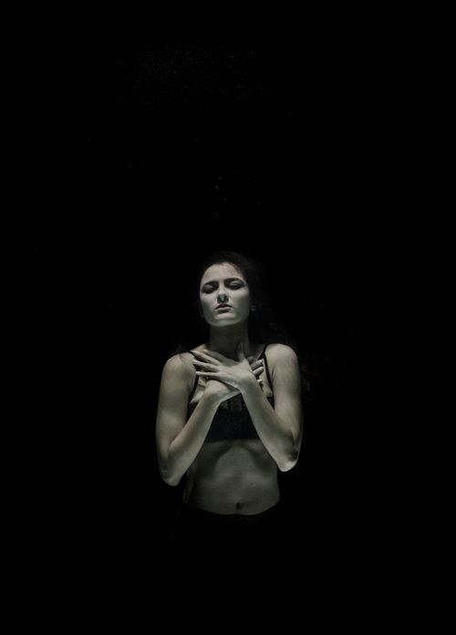 Free A serene and emotive underwater portrait capturing a young woman in black attire, exuding elegance and mystery. Stock Photo