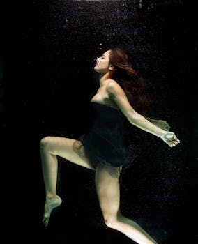 一位身穿黑色连衣裙的女子在水下翩翩起舞，姿态优雅