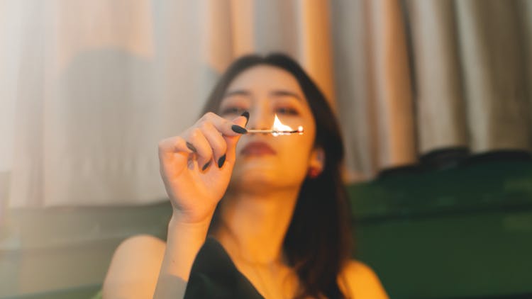 A Woman Holding A Lighted Match