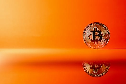 Golden Bitcoin with reflection on a bright orange background, representing digital currency concepts.