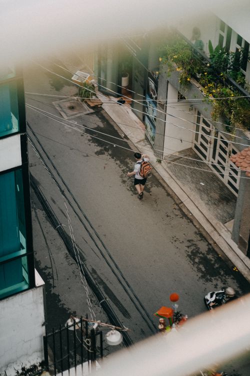 Free Young man walking down a narrow urban alley, captured from above, showcasing city life. Stock Photo