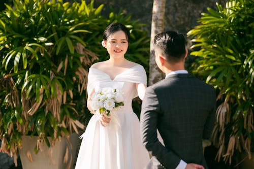 Photo of a Bride with a Bridal Bouquet Looking at a Groom