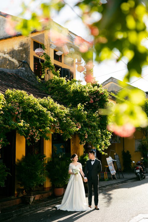 Bride and Groom Holding Hands While Standing in the Street