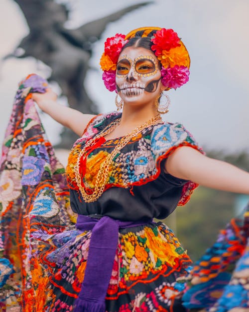 Woman Wearing a Colorful Traditional Mexican Dress with Floral Headdress and Skull Makeup