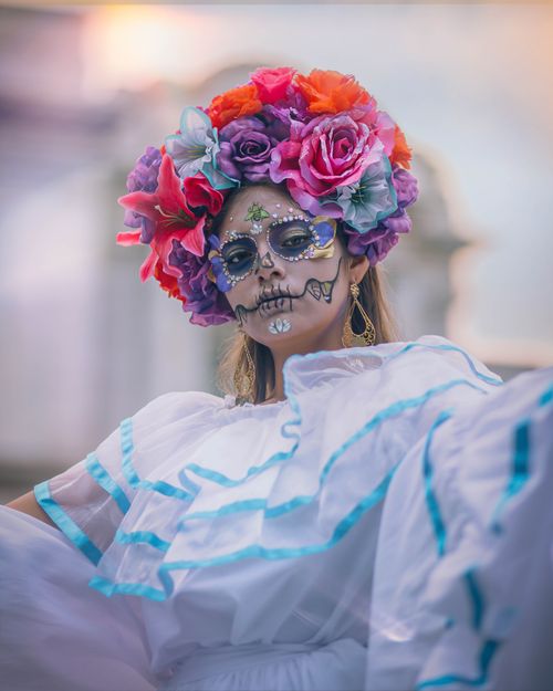 Free A woman in traditional Day of the Dead attire with floral headdress and face paint in Mexico City. Stock Photo