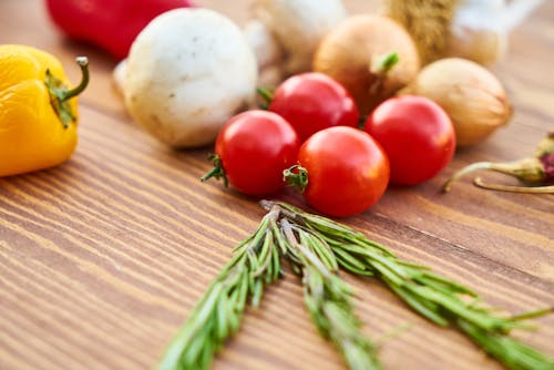 Red Tomatoes Near Rosemary and Other Spices Close-up Photography