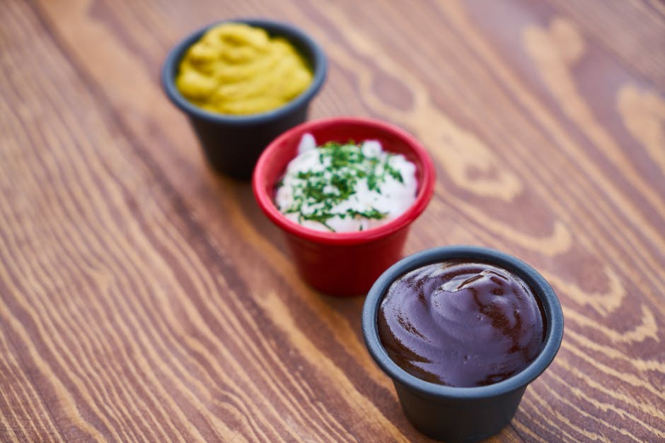 Three Assorted-color of Cream in Containers on Brown Wooden Slab