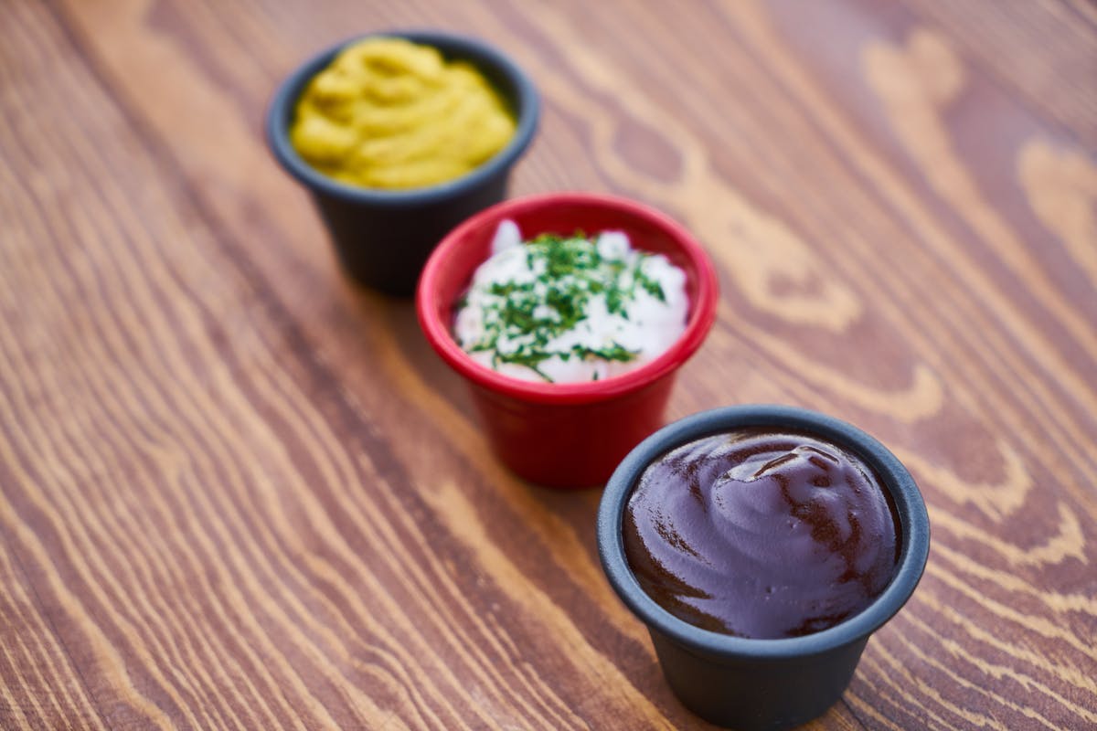 Three sauces in cups on a wooden surface