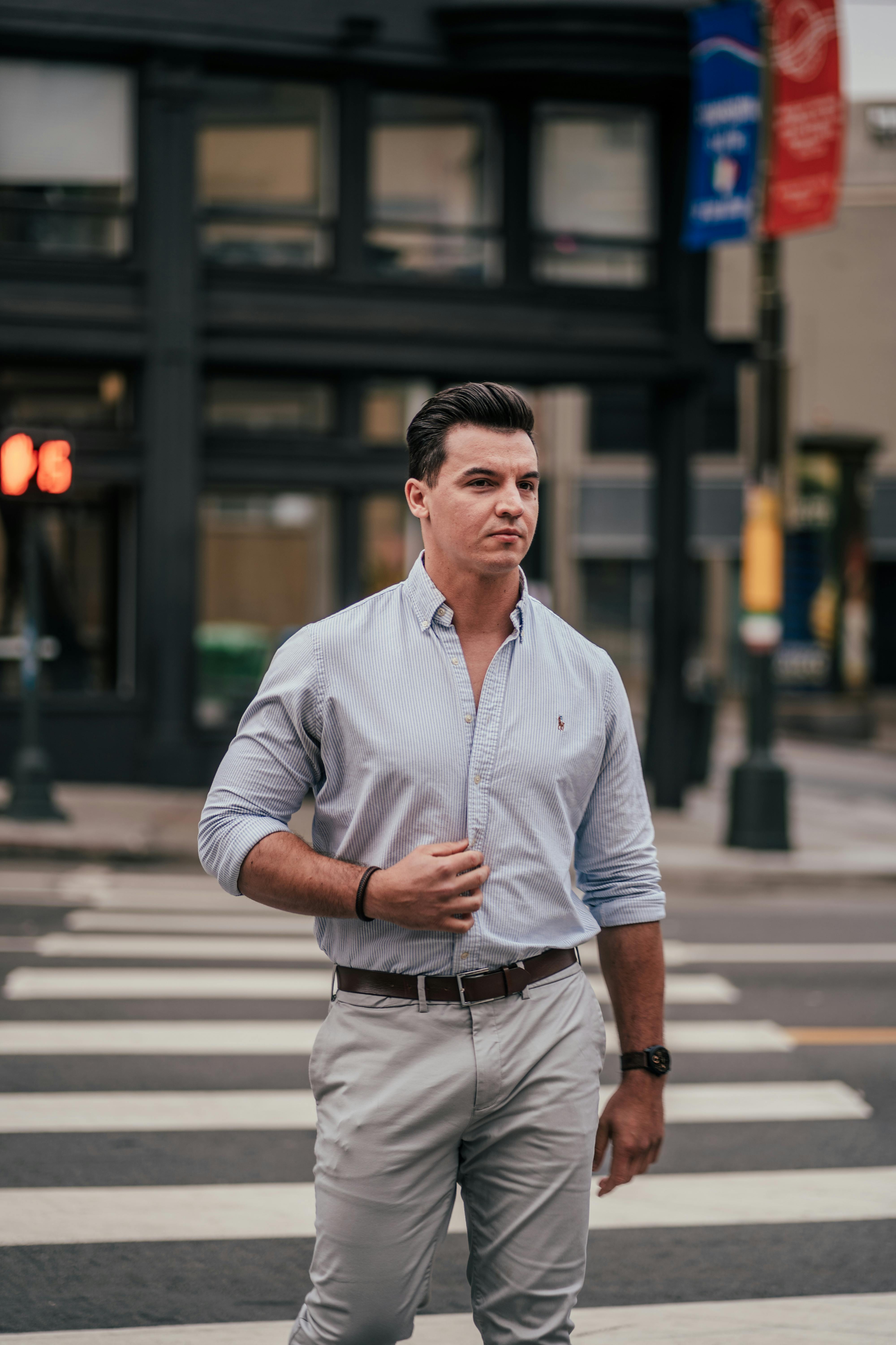 Man in Blue Polo Shirt and Gray Pants Standing on the Street while Seriously Looking at the Camera Free Stock Photo