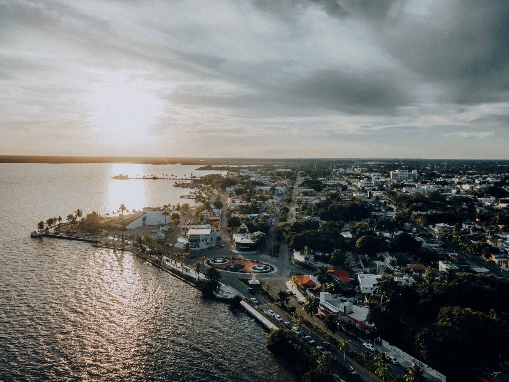 Stunning aerial shot capturing a coastal city with dramatic skies at sunset.