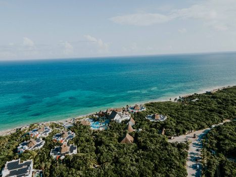 Stunning aerial view of a luxury beachfront resort surrounded by lush greenery in Tulum, Mexico.