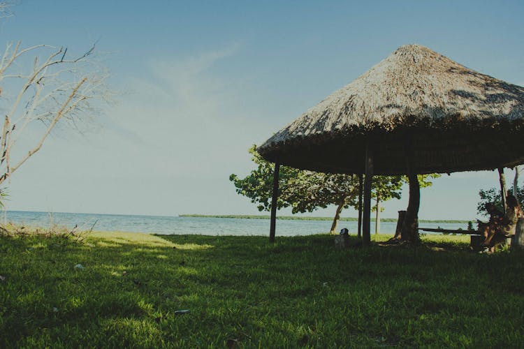 Beach Hut On Green Grass Field Near Body Of Water