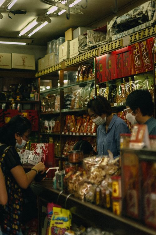 Free Masked individuals shopping at a well-stocked oriental grocery store amid a bustling atmosphere. Stock Photo