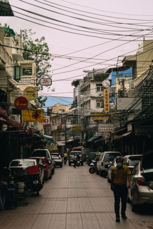 Free City street scene with overhead cables and parked vehicles, conveying urban energy. Stock Photo