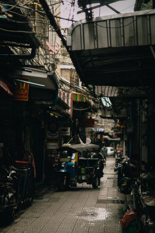 Free Moody city alley with an auto rickshaw and shops, creating a vibrant urban atmosphere. Stock Photo