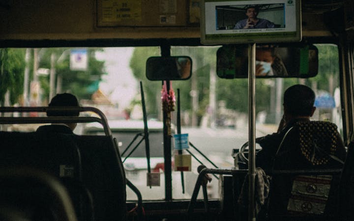Inside view of a public bus featuring passengers during a daytime commute.