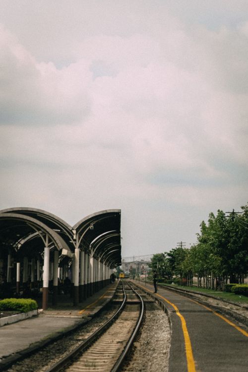 Free Peaceful and quiet train station with empty railway tracks extending into the distance. Stock Photo