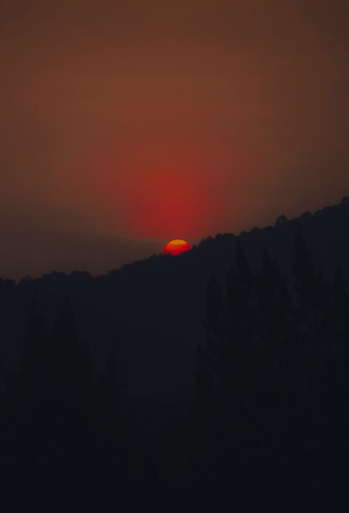 Free A striking image of the sun setting behind a mountain, casting a warm orange glow. Stock Photo