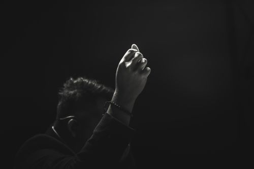 Free Artistic black and white image of a raised hand in focus against a dark background. Stock Photo