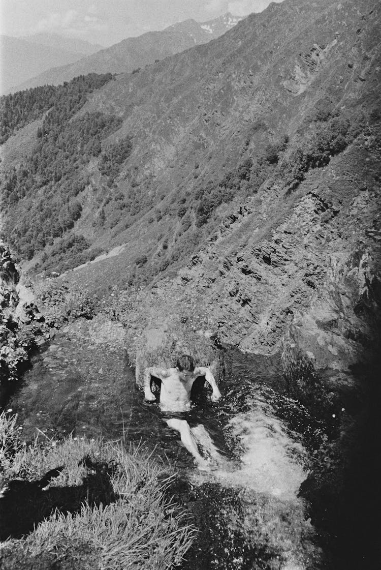 Grayscale Photo Of A Man Swimming On The River 