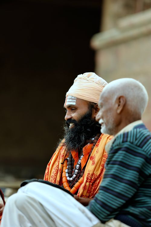 Free Two Indian men engage in a warm, spiritual conversation outdoors, showcasing cultural attire and tradition. Stock Photo