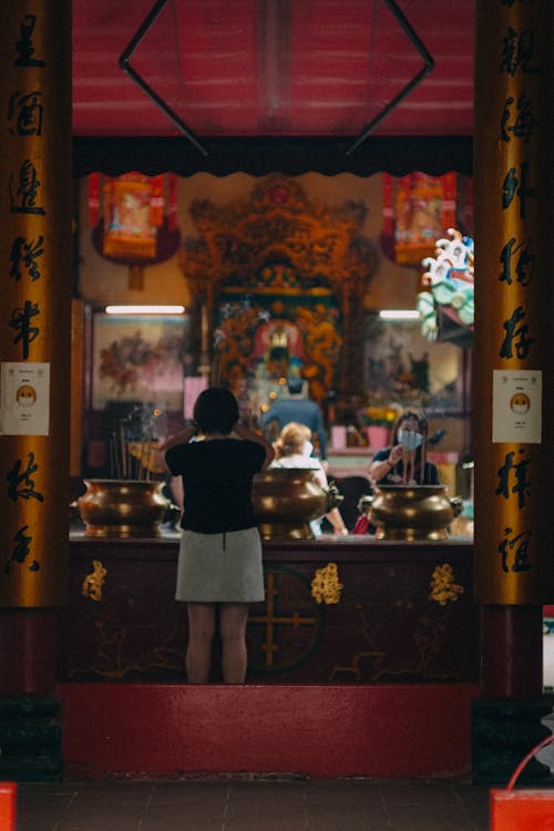 Person in Black Shirt and Gray Mini Skirt Standing Inside a Buddhist Temple