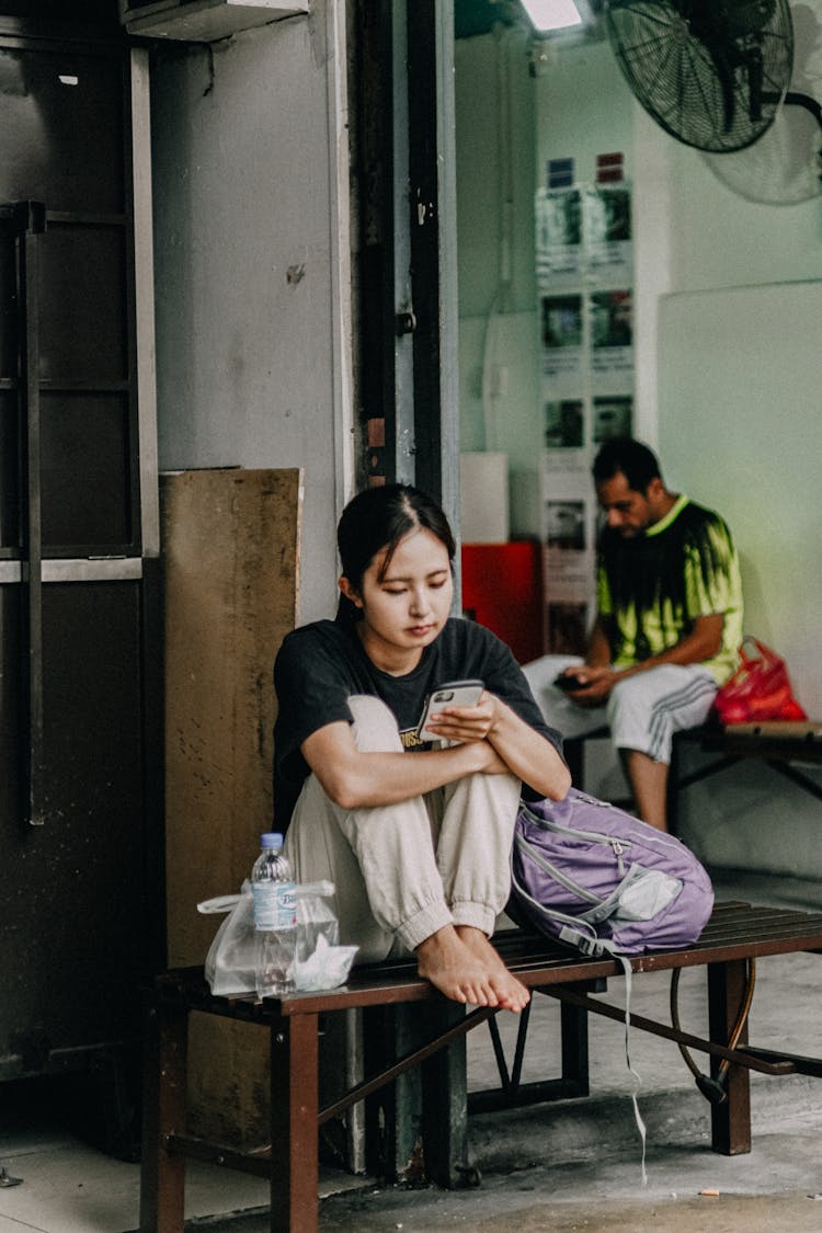 A Woman Sitting On The Bench While Using Smartphone 