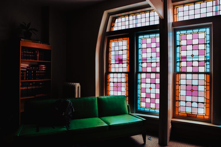 Green Leather Couch Beside Of Stained Glass Window