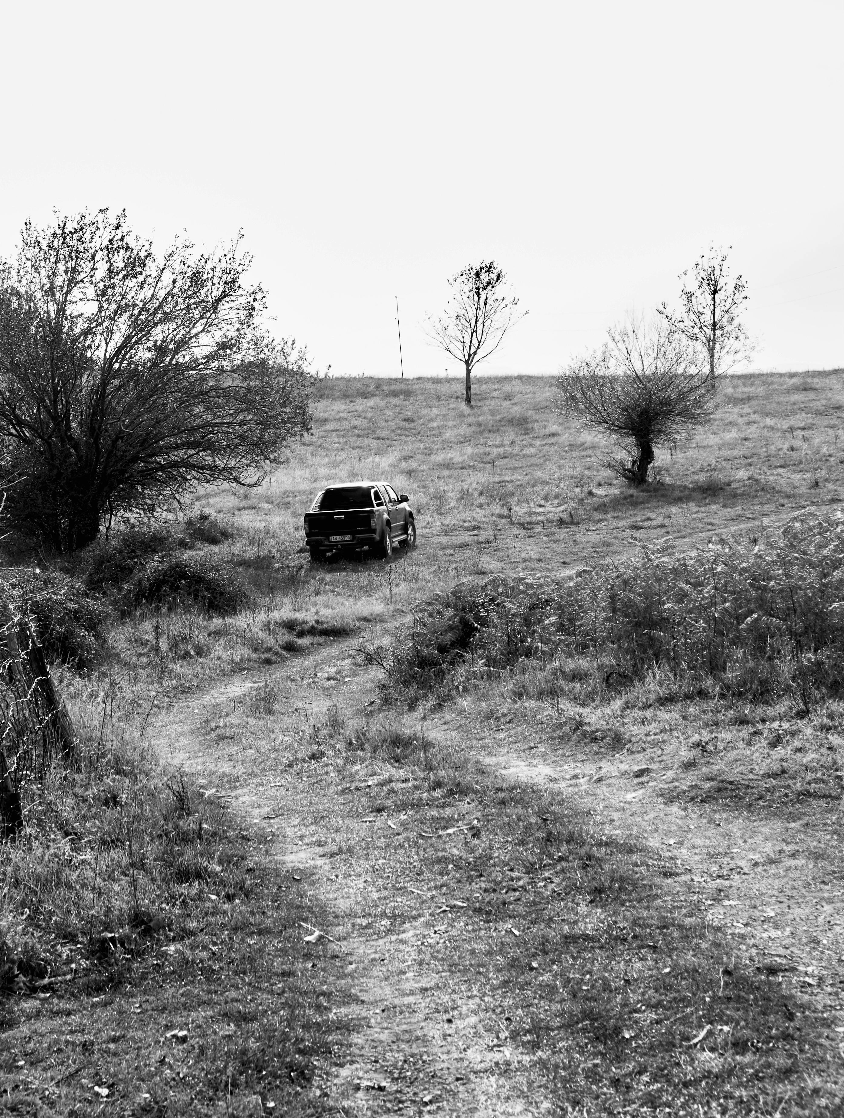 Black and white image of a car on a rural offroad path in Gurth Spaç, Albania.
