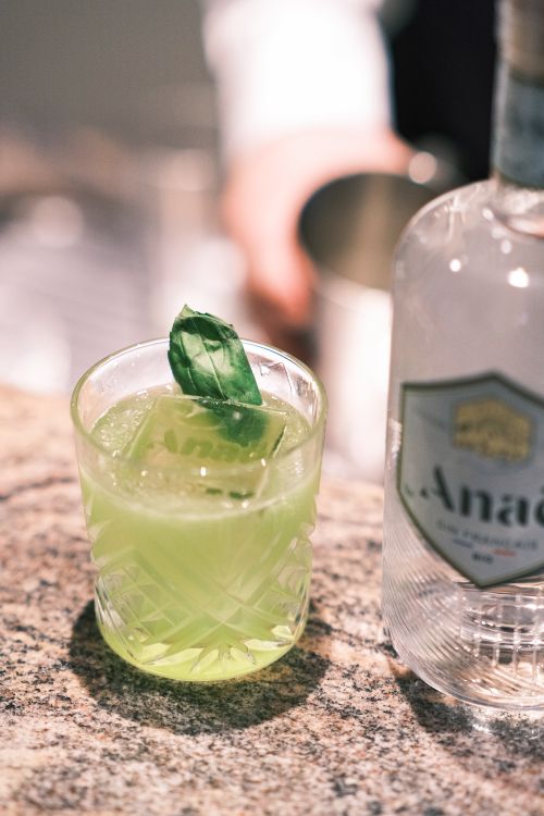 Free Close-up of a green cocktail with basil leaf garnish, perfect for a refreshing drink experience in Paris. Stock Photo