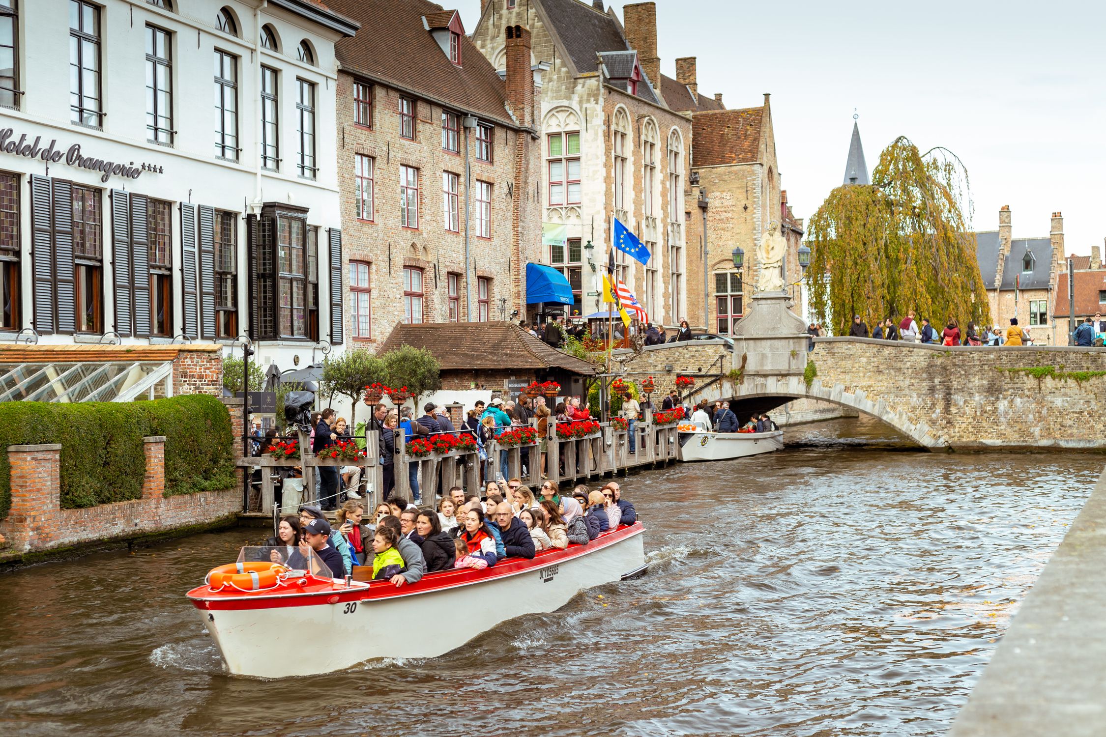 Tourists enjoying a scenic boat tour along a historic canal in Bruges, Belgium.