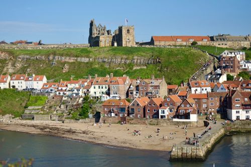 Free Aerial view of Whitby Abbey and seaside town with colorful houses under a blue sky. Stock Photo