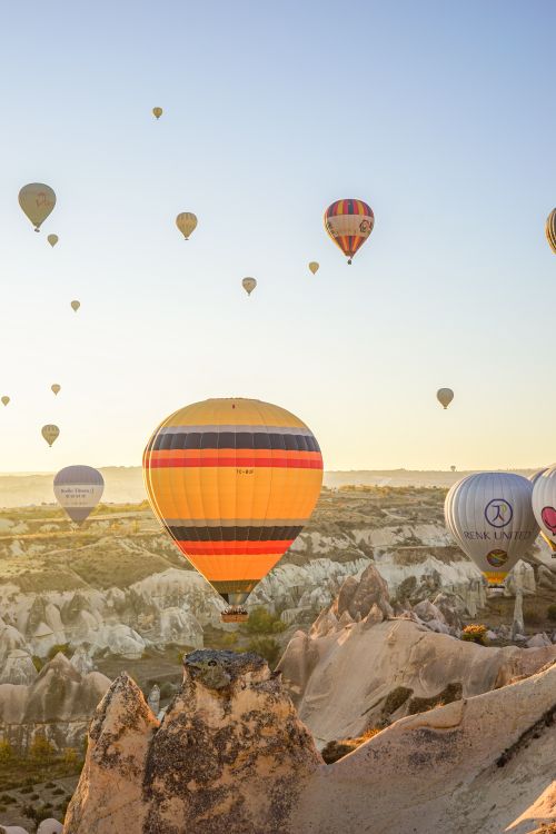 Free Vibrant hot air balloons soar over the unique rock formations of Cappadocia at sunrise. Stock Photo