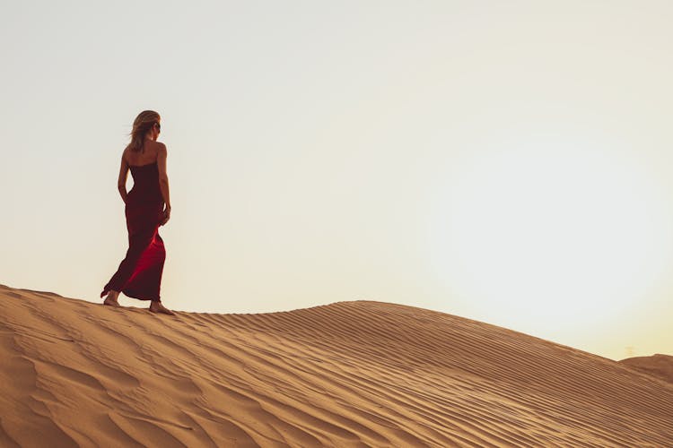 A Woman In Red Dress Walking On Desert 