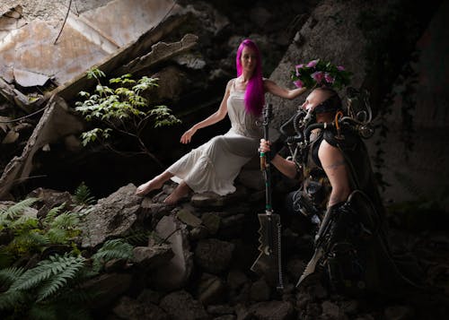 Woman With Purple Hair Wearing White Sleeveless Dress Sitting on the Rocks Holding Pink Floral Headband