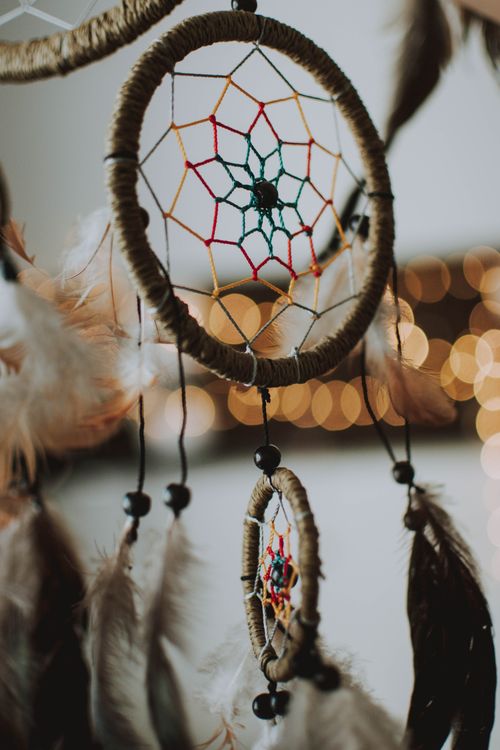 Free Artistic photo of a dreamcatcher with delicate feathers and a warm bokeh background, ideal for bohemian themes. Stock Photo