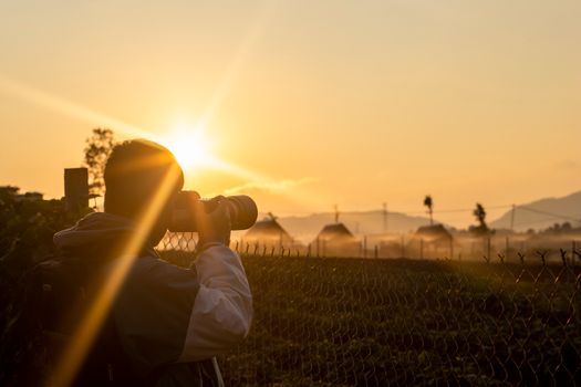 Silhouette of a photographer taking a sunset landscape photo outdoors.
