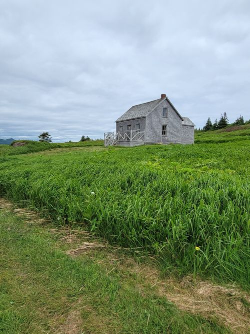 Free Charming old house nestled in green fields under a cloudy sky in Percé, QC, Canada. Stock Photo