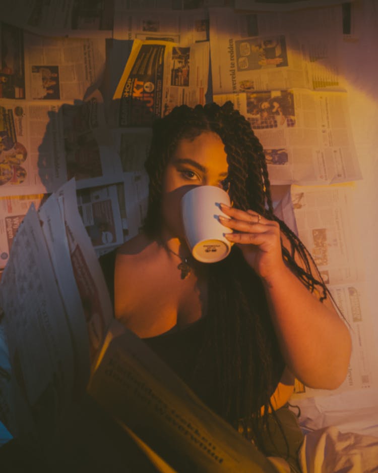 Woman Drinking From Cup On Newspapers Background