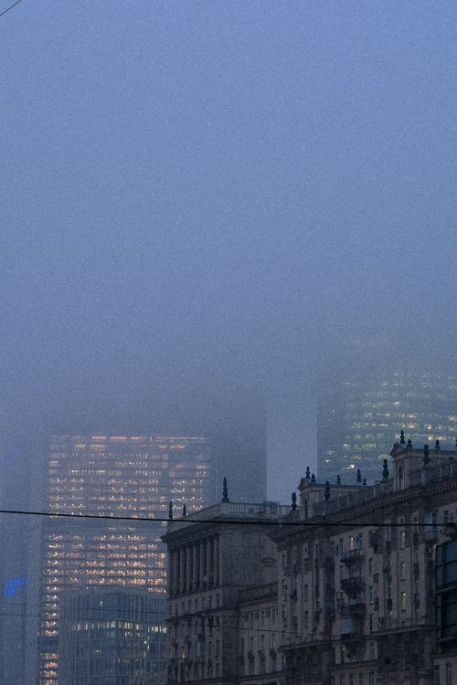 Free Mystical urban skyline with fog-covered skyscrapers and historical architecture during the evening. Stock Photo