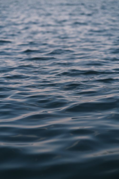 Free Serene ocean waves gently ripple under soft twilight, evoking peace. Stock Photo