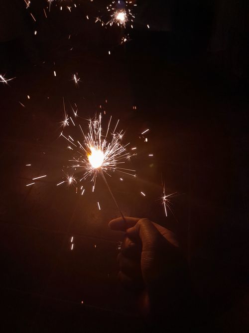 Free A person holding a sparkler at night, illuminating the darkness with bright sparks. Stock Photo